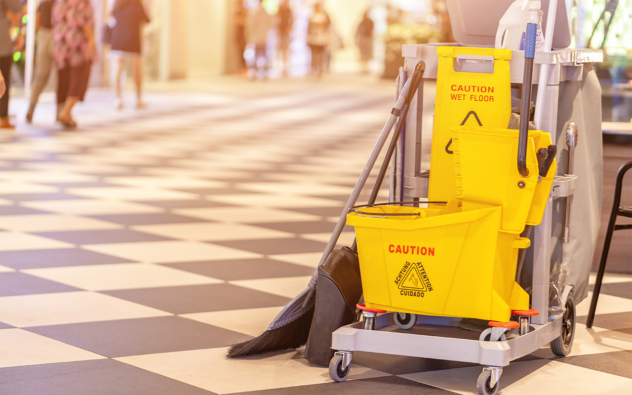 Janitorial Cart with a broom, mop bucket, dust pan and a yellow wet floor sign typically used by a cleaning business.
