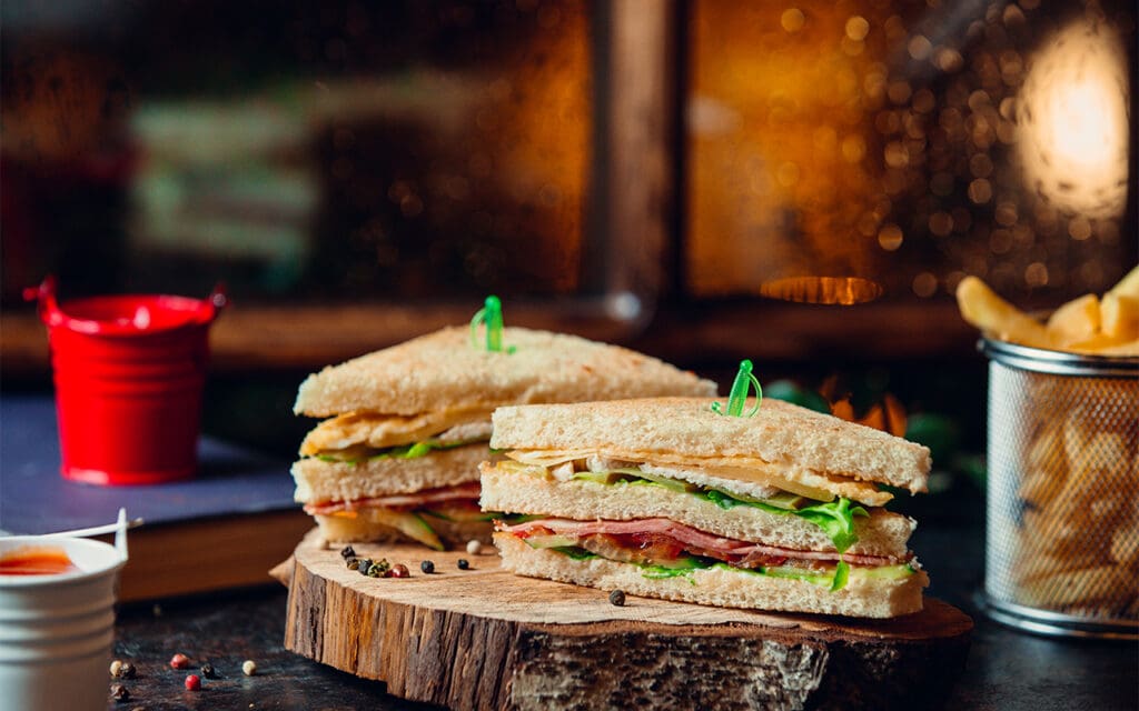 Sandwich cut in half with green sword picks in the middle that can be found in a deli for sale.