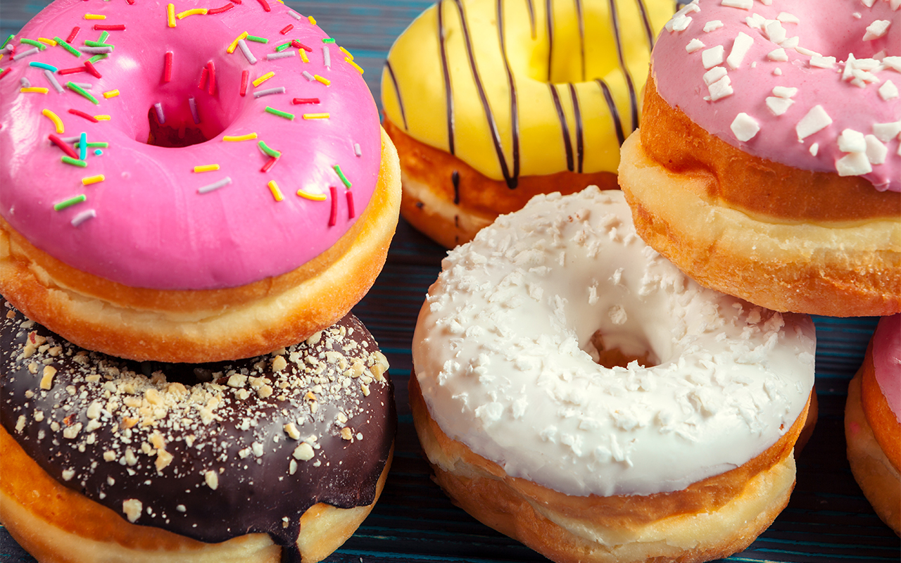 Variety of donuts with different types of frostings and toppings that can be found in a donut shop for sale.