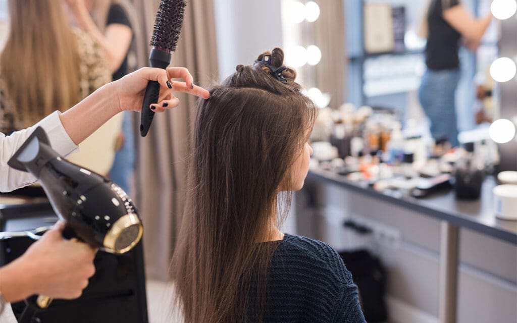 A female customer getting her hair done by a professional hair stylist that works at a hair salon for sale.