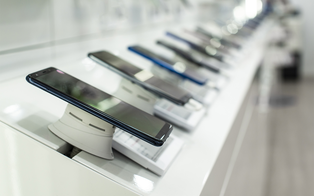 Row of modern smart phones that are displayed in a typical mobile business for sale.