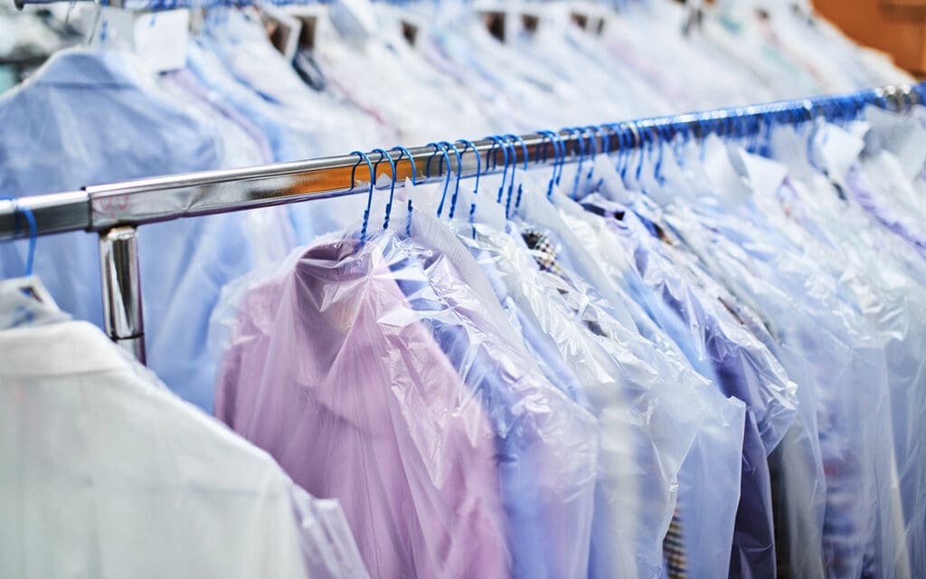 A rack with button down shirts inside a dry cleaners business that can be seen in a dry cleaner for sale.