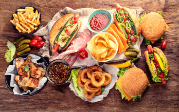 A table set with a variety of foods including burgers, fries, onion rings and more that can be found in a typical fast food franchise for sale.